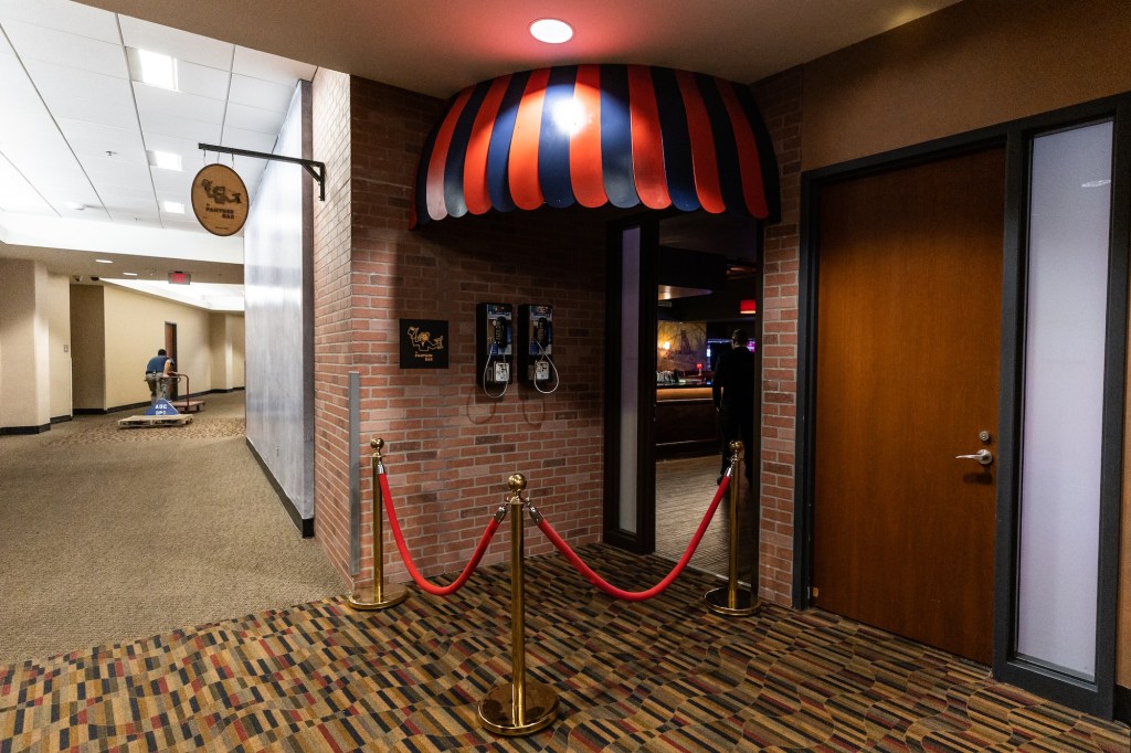 Photo of a door in the middle of a hallway. The door has a an awning and a velvet rope in front of it