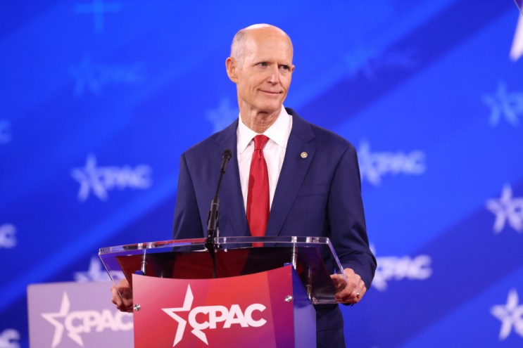 A bald man speaking at a red podium that reads "CPAC"r