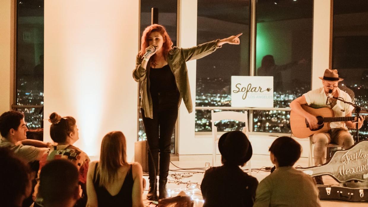 Photo of a woman singing on a microphone on a stage.