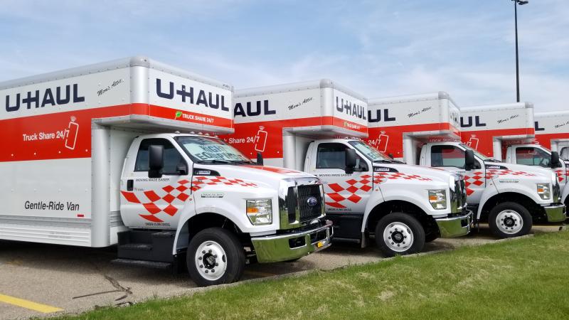 five moving trucks in a row sitting in a parking lot