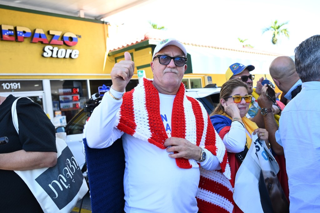 photo of a man at a rally draped in a crocheted American flag