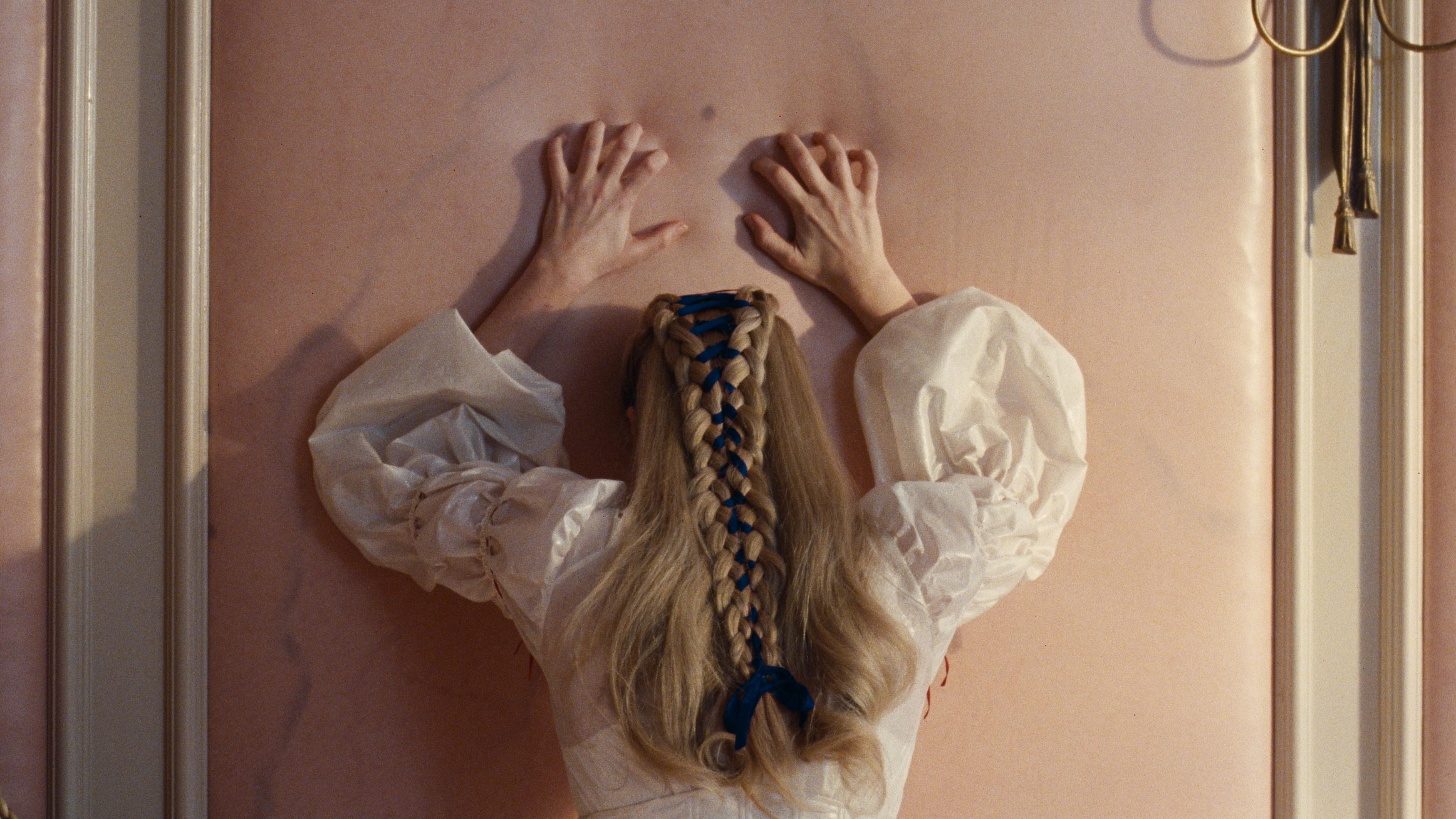 photo of a blonde woman pressing her hands up against a plush wall