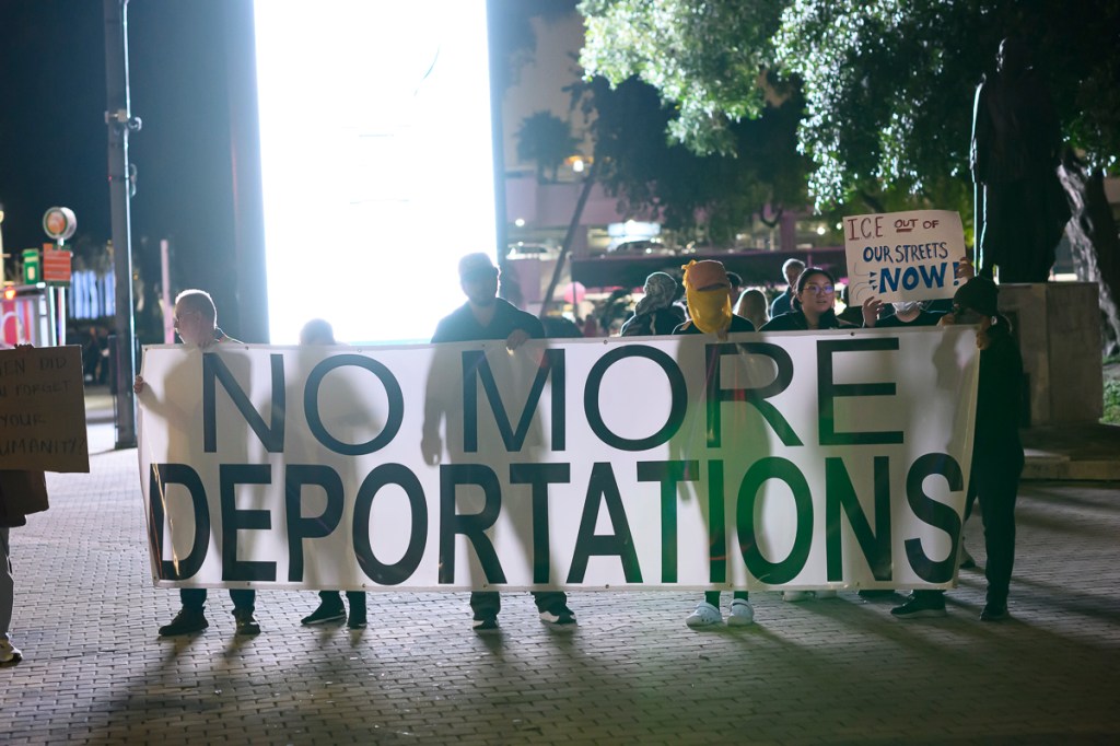 photo of protesters holding a banner reading, "No more deportations"