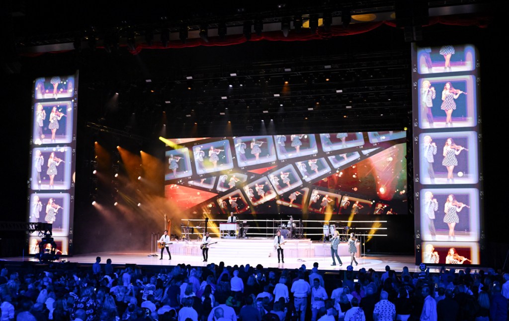 Photo of a stage with screens showing many photos 