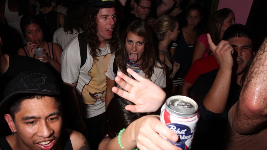 photo of young people dancing holding a beer can. 