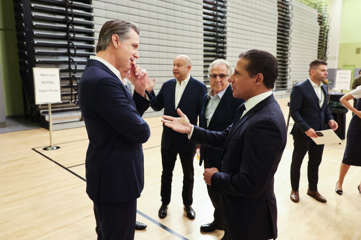 photo of California Gov. Gavin Newsom (left) and Alberto M. Carvalho (right) in conversation with several people standing behind them
