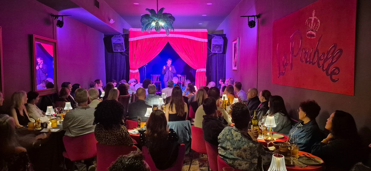 Photo of a small red room with a performer on stage.