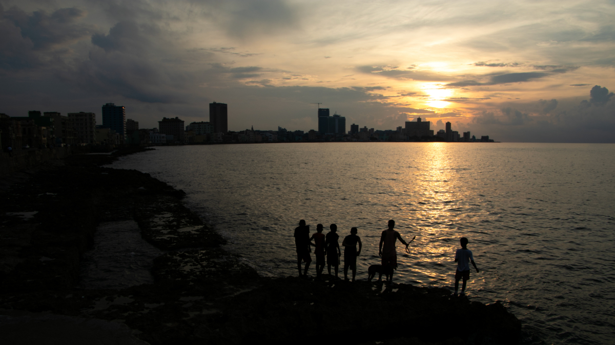 Children standing by a coastline at sunset.