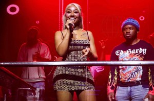 photo of rapper Yung Miami performing on a balcony stage in a club