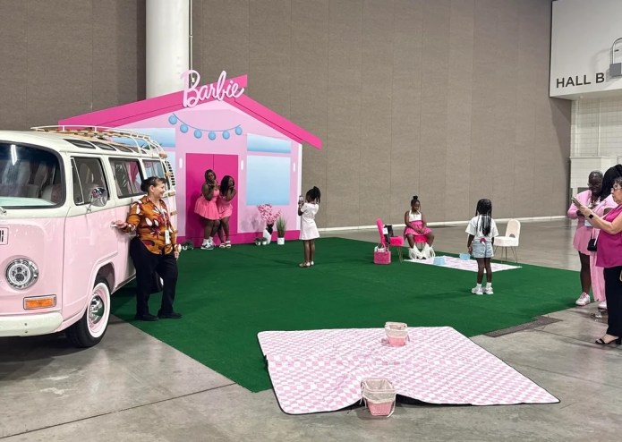 photo of young girls posing for photos with a Barbie house in the background