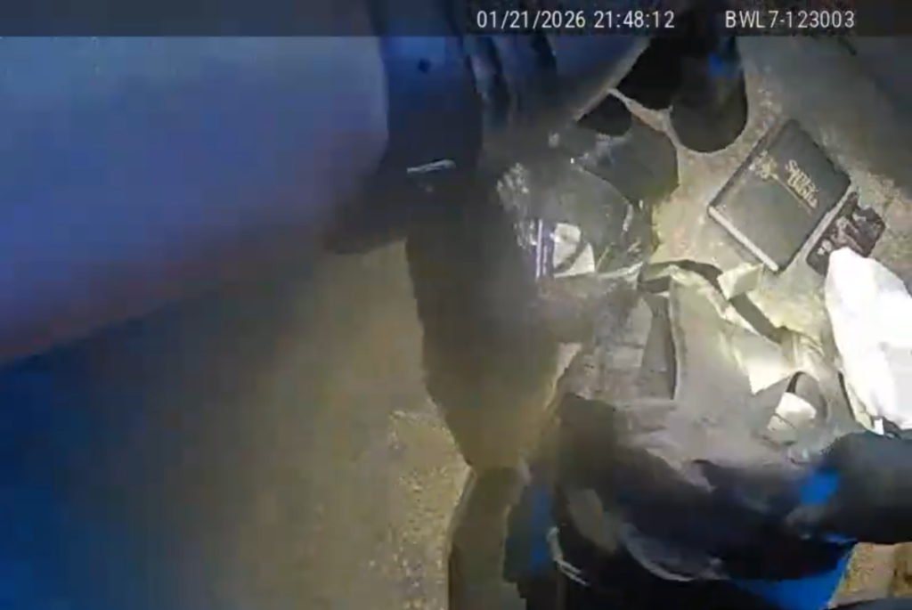 A screenshot from police body-cam footage showing a backpack on the ground next to a Bible.