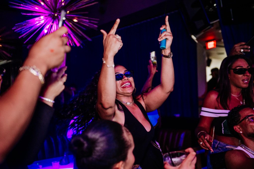 Photo os a woman at a club dancing with her hands up.