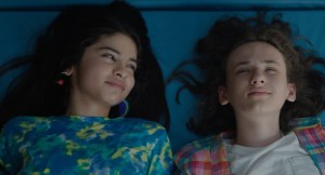 Still from the film 'Ethan Bloom' showing an overhead view of a young boy and older girl lying down. The boy looks up at the sky and the girl looks at the boy