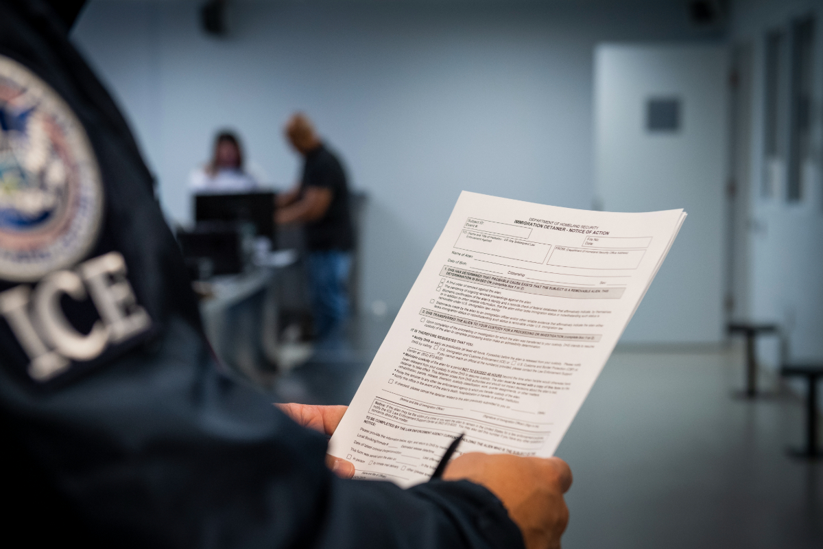 A photo of an ICE officer holding paperwork.
