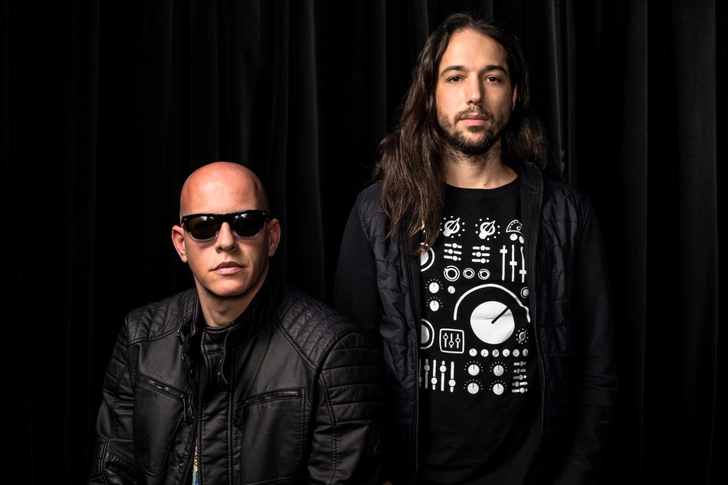 photo of the two musicians of Infected Mushroom posing together in black shirts and jackets