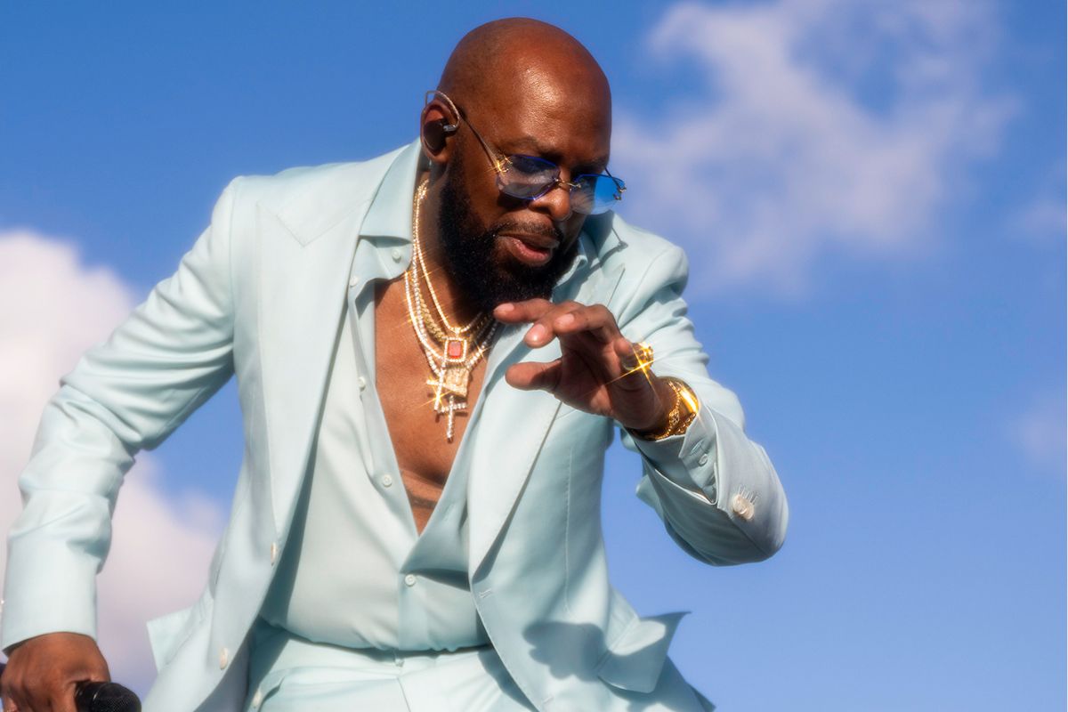 Photo of a man wearing a light blue suit dancing during the day