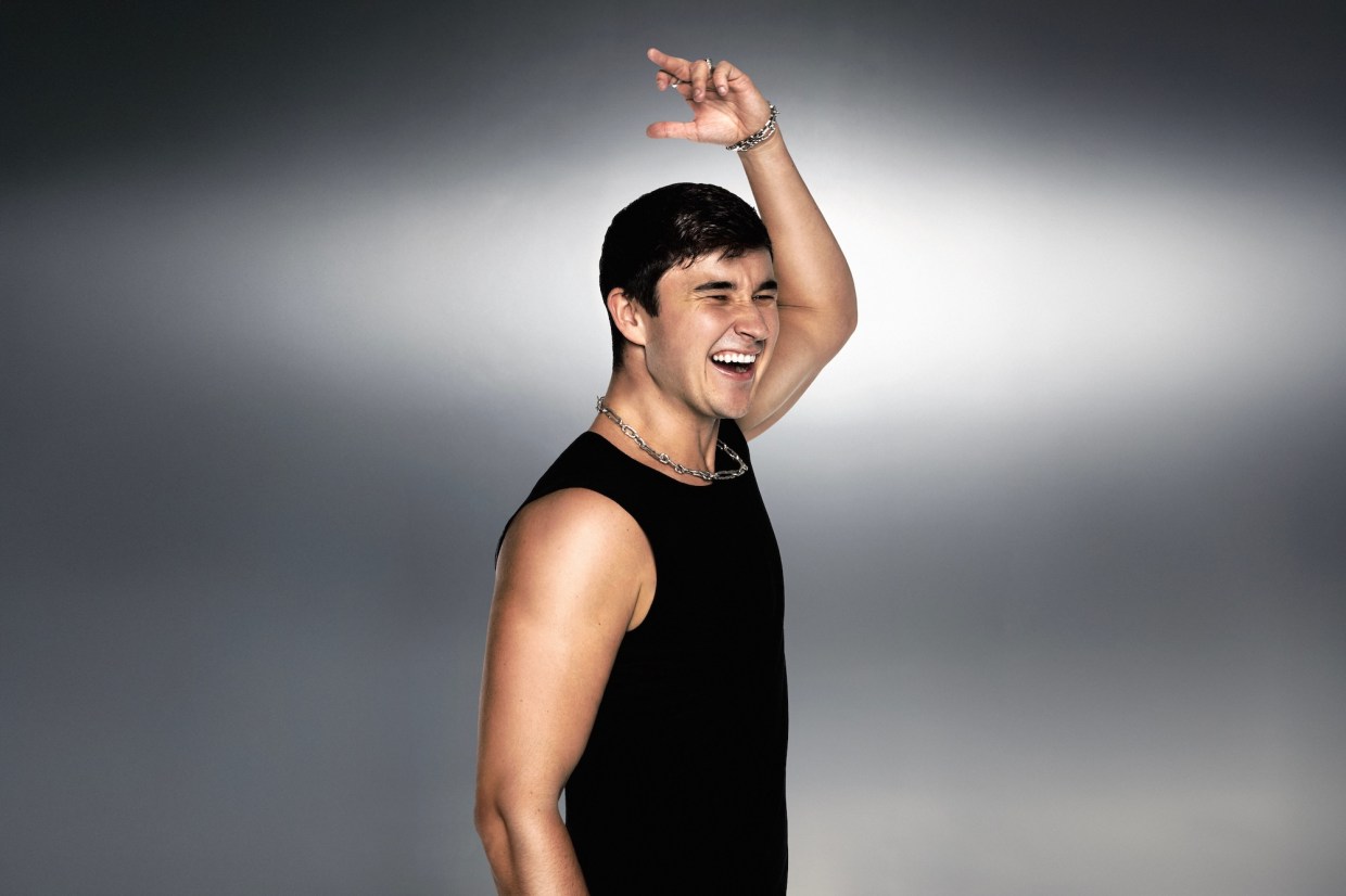 Photo of a man with a sleeveless black shirt raising a hand in the air.