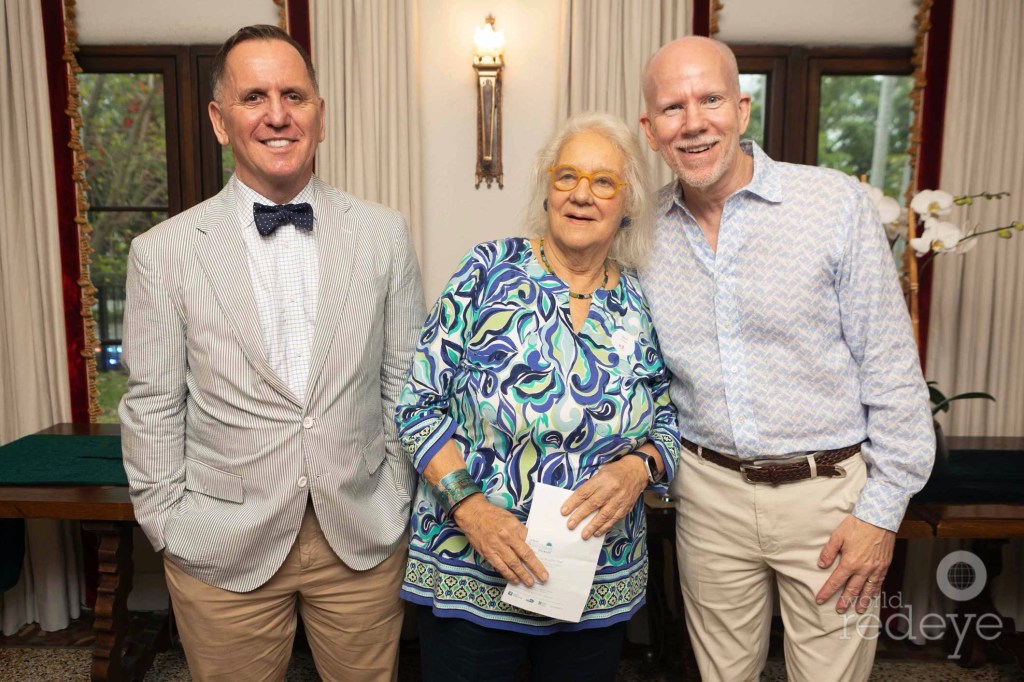 photo of a man in a suit, an older woman in a colorful blouse, and another man in a button-down suit and slacks all posing together