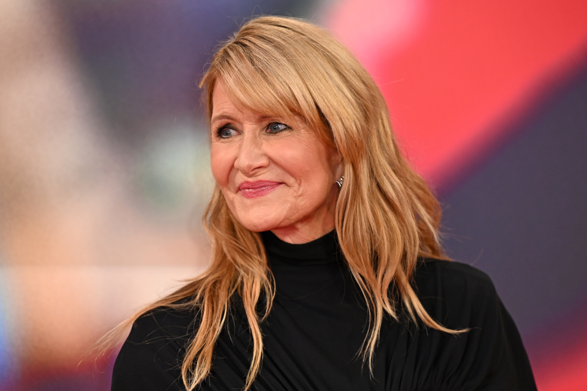 A photo of a blonde woman with side bangs smiling in front of a camera