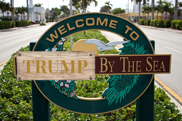A sign of Lauderdale by the Sea where the Lauderdale is covered by a illustration of a piece wood that says, "Trump" in gold.
