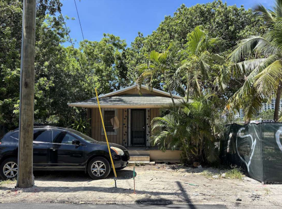 Google Maps street view photo of small house with a car in front surrounded by trees