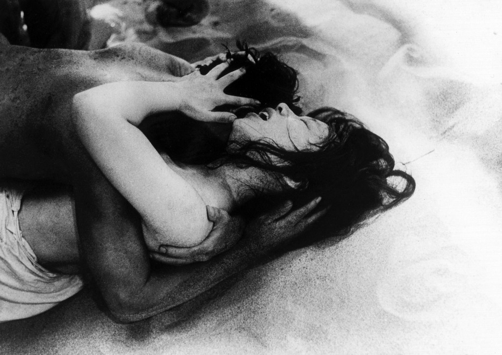 black-and-white still from the film "Woman in the Dunes" showing a man and woman in the throes of passion