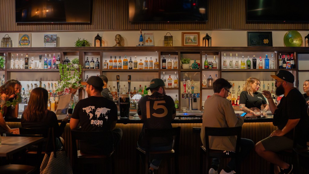 a dimly lit bar with people sitting at the bar talking to one another