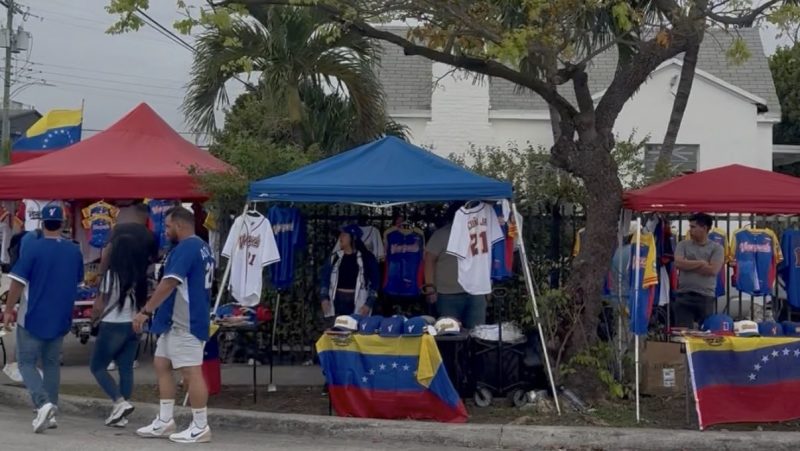 photo of three tents selling Venezuela merch before the World Baseball classic with crowds gathering to buy jerseys and flags