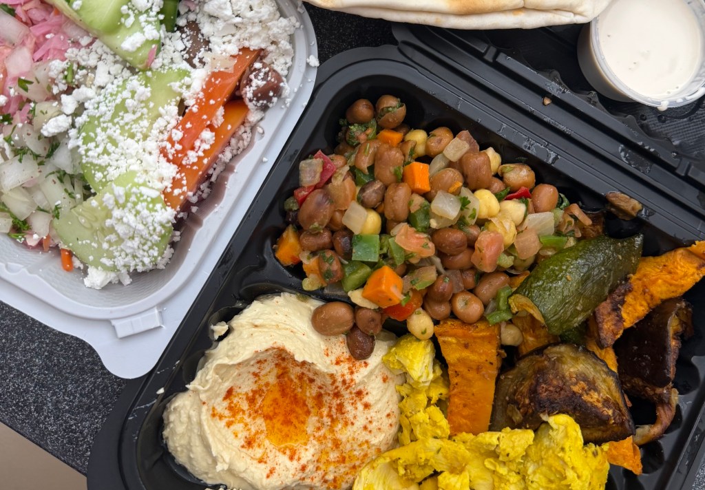 a takeout order of delicious chicken, hummus, and a Greek salad to the side
