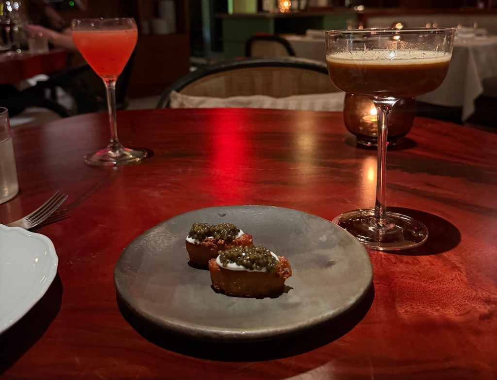 A fun tiny caviar appetizer and two cocktails on a table at Fooq's