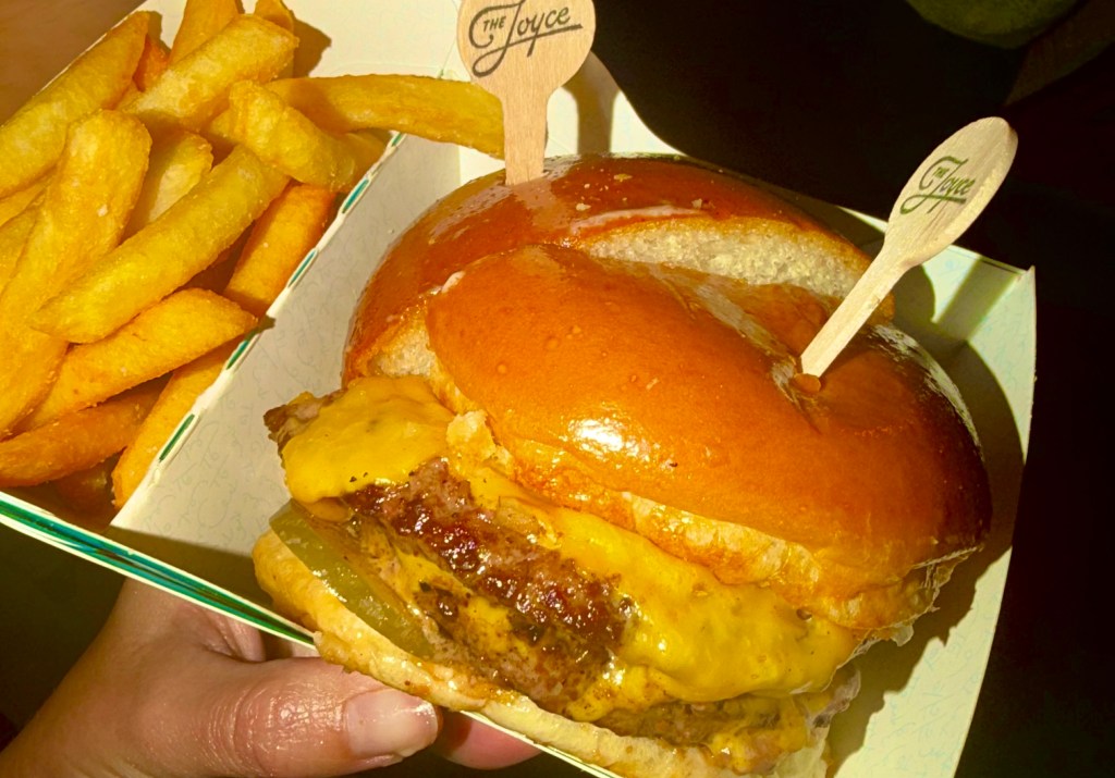 a delicious photo of a  cheeseburger with a side of fries taken at night