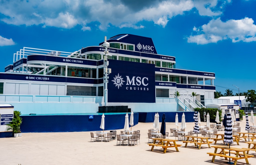 photo of yacht club designed to look like an MSC Cruises ship with picnic tables and umbrellas in the foreground
