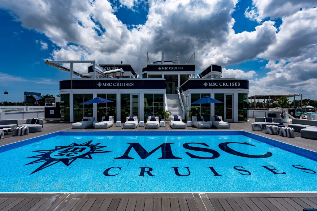 Photo of a yacht club with a pool in front. The pool logo reads, "MSC Cruises"