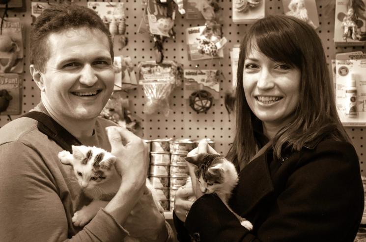 A photo with a sepia effect of a man and woman holding small kittens.