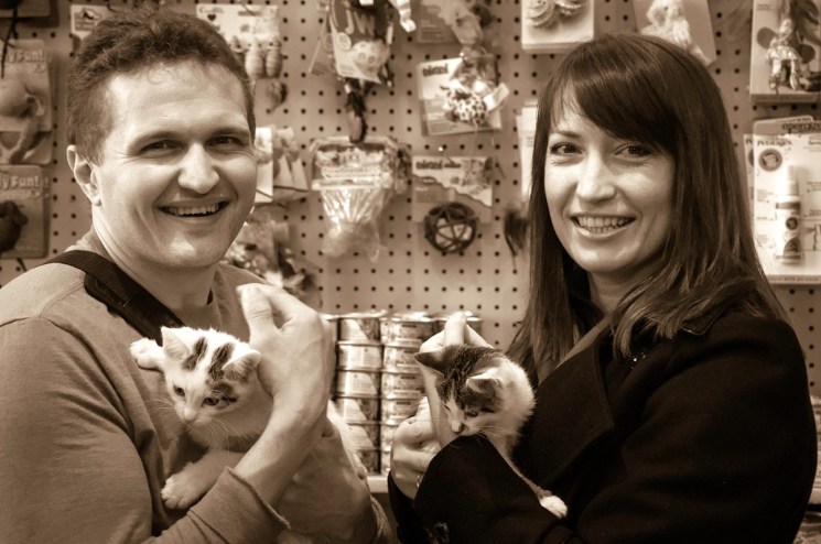 A photo with a sepia effect of a man and woman holding small kittens.