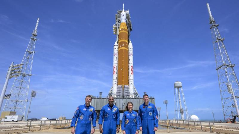 photo of the crew of Artemis II standing in front of its rocket in front of blue skies