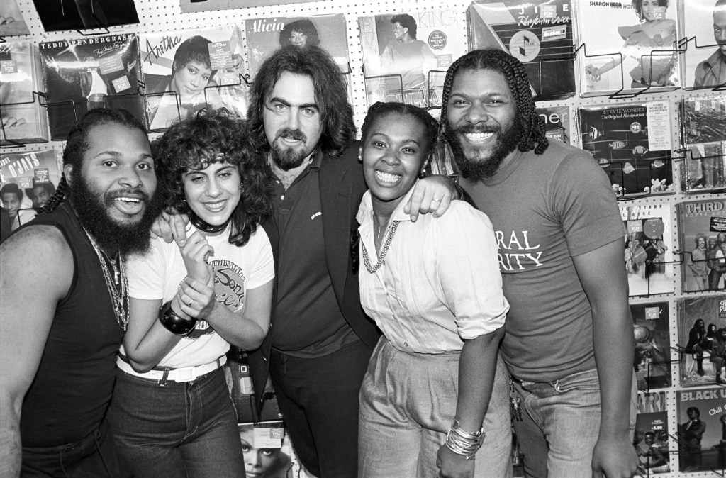 black-and-white photo of five musicians posing together inside a record shop