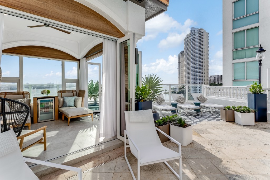 Photo of a private cabana with a mini-fridge and lounge chairs. The ocean and Miami cityscape can be seen in the distant background