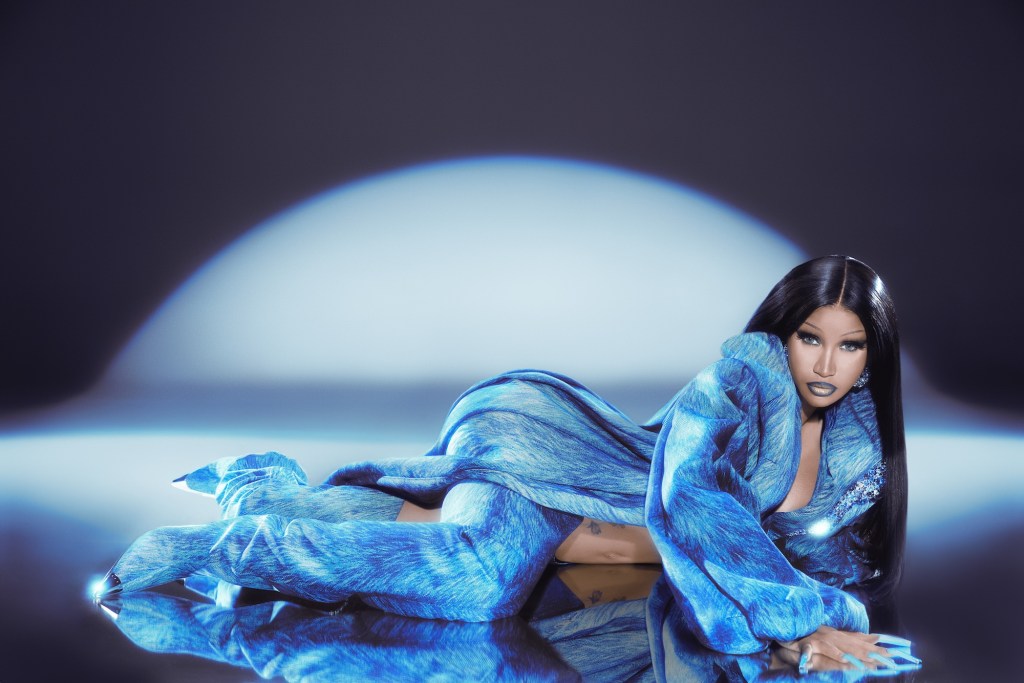 photo of rapper Cardi B lying sideways on the ground in a long, black wig and blue denim coat with matching boots