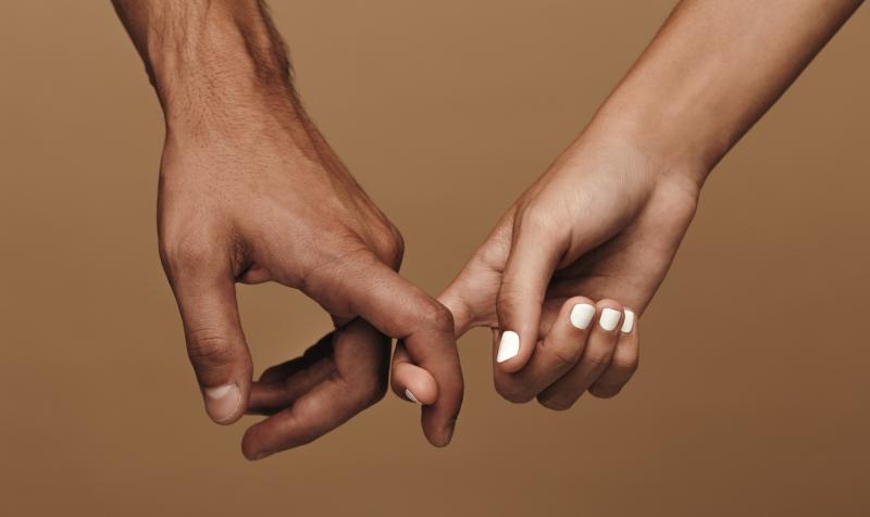 Close-up photo of a couple linking index fingers