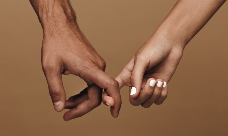 Close-up photo of a couple linking index fingers