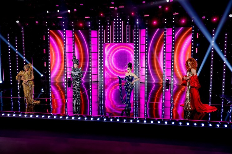 photo of four drag queens with elaborate costumes on a stage with a purple backdrop