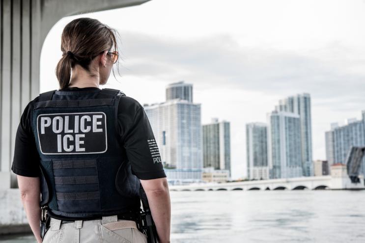 An ICE officer looks out over the Miami skyline.