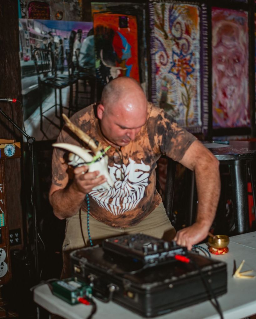 Photo of a man on stage making music with a goat skull in Miami