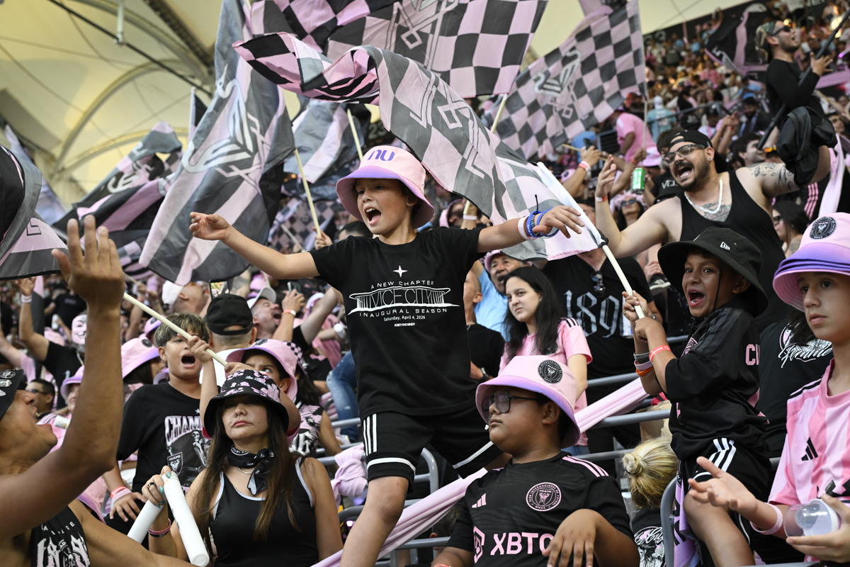 photo of soccer fans wearing pink and black and waving pink and black flags at an Inter Miami FC game