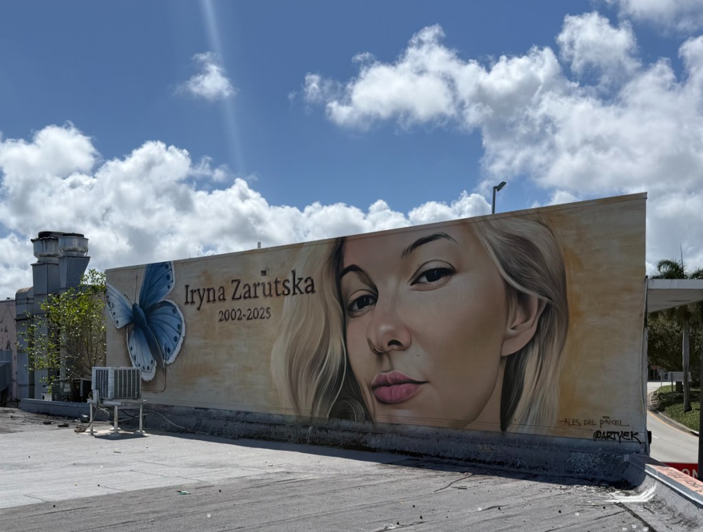 A photo of a mural of a young blonde woman on the side of a building.