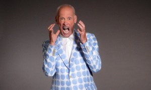 photo of director John Waters making a shrieking face while wearing a white-and-blue polka dot suit