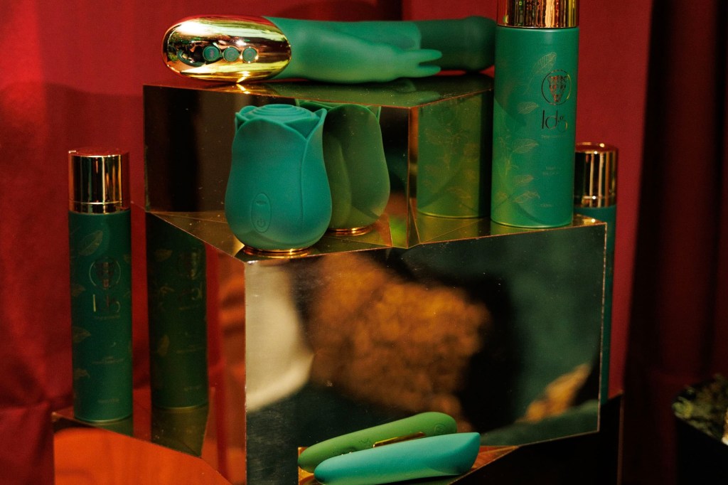 photo of a gold package with green sex toys on display on top and beside it