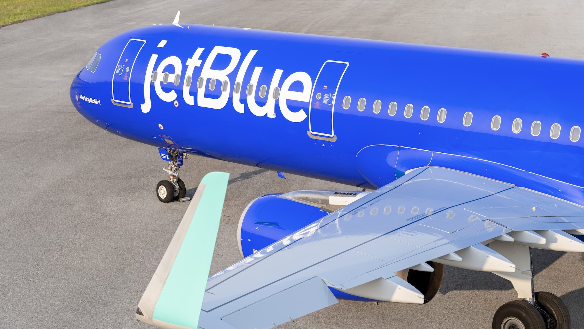 photo of a JetBlue plane with a blue livery on the runway