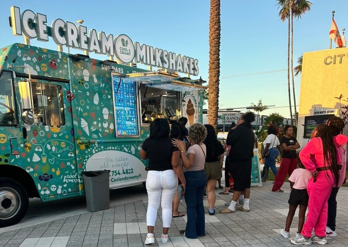 photo of people waiting in line in front of a food truck selling ice cream and milkshakes